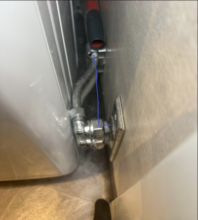 Rörinstallation med 90-graders vinkel böjer sig längs väggen nära en apparat.