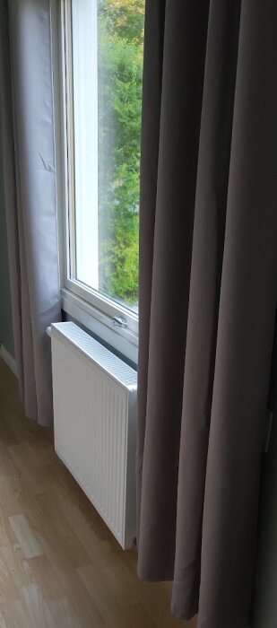 Ett nytt element installerat under ett fönster med mörka gardiner, elementet täcker delvis utsikten.