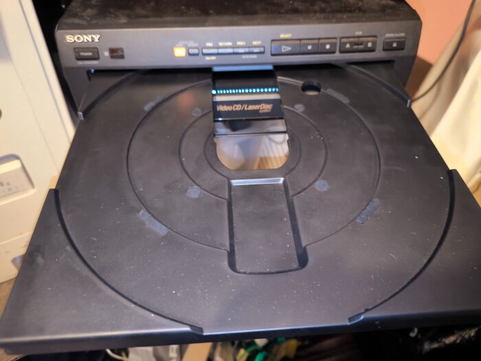 Sony LaserDisc-spelare med öppen skivfack. Enheten har knappar för drift och ett fack för Video CD och LaserDisc-skivor, samlar damm i förrådet.