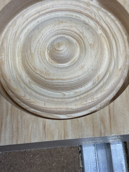 CNC-fräst träbit med cirkulärt, räfflat mönster i ljus träfärg, del av ett projekt för skärbrädor med olika typer av träslag.