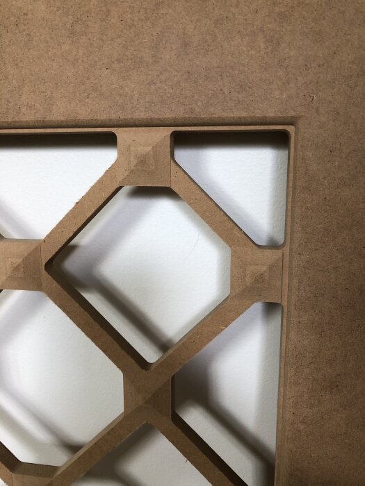En detaljerad träpanel med hexagonalt mönster fräst med CNC-maskin, del av ett hemmabygge med flera olika träprojekt.