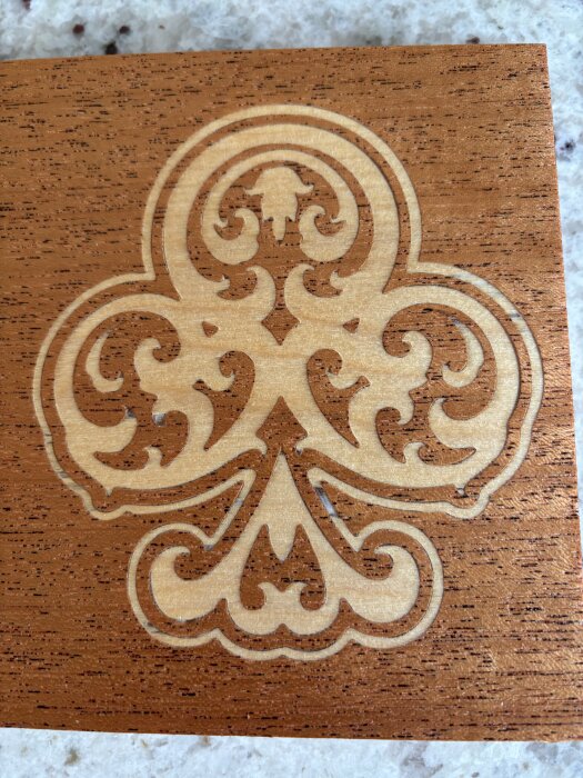 Ingraverat trästycke i mörkt trä med ett ornamentalt mönster fräst av CNC-maskin, inspirerat av olika kreativa designidéer.