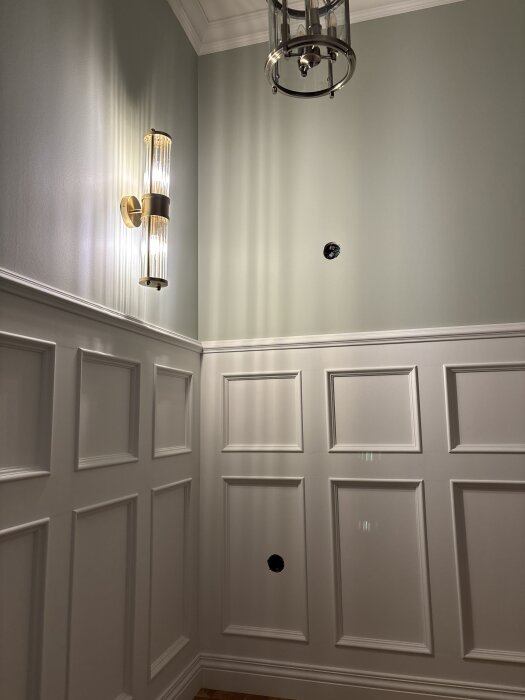 Vägg med panel och håltagning för inbyggnadslampa, elegant ljusarmatur och taklampa, del av renoveringsprojekt med CNC-fräsning.
