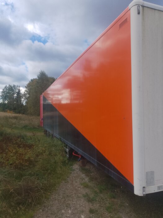 Orange och svart lastbilssläp på landsväg; släpet har potentiella problem med stödbenet enligt diskussionen.