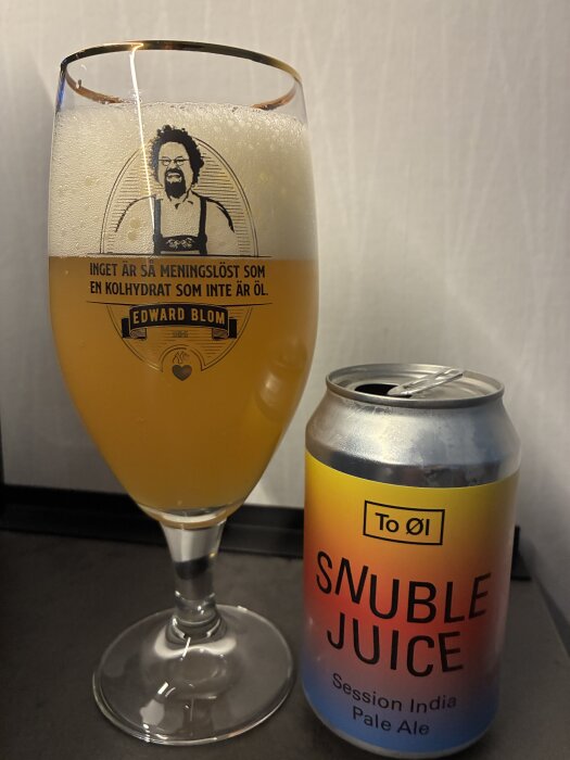 Glas med öl och burk med etikett "To Øl Snuble Juice Session India Pale Ale" på ett bord.