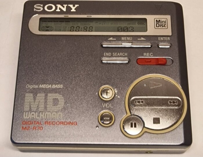 Sony MZ-R70 MiniDisc-spelare med display och knappar, inklusive volymkontroll och spel-/pausknappar.