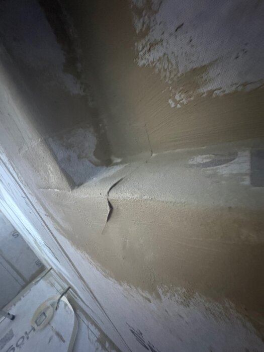Glapp mellan tätskikt och tak i ett badrum, våtzon 1. Misstänkt felaktig installation av tätskiktet där struktur och sprickor syns.