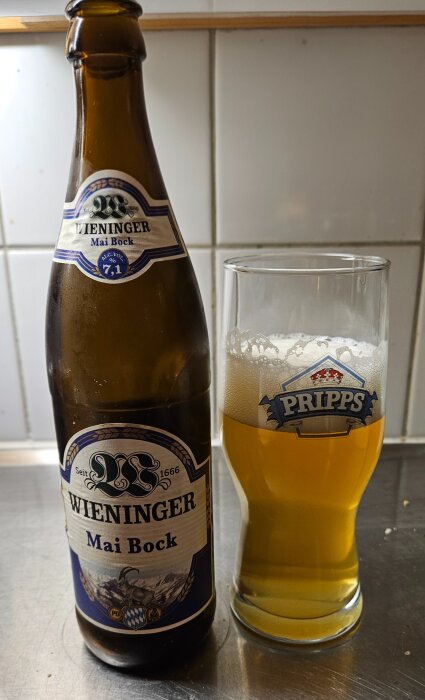 Flaska med Wieninger Mai Bock öl bredvid ett fullt Pripps-glas på en köksbänk.