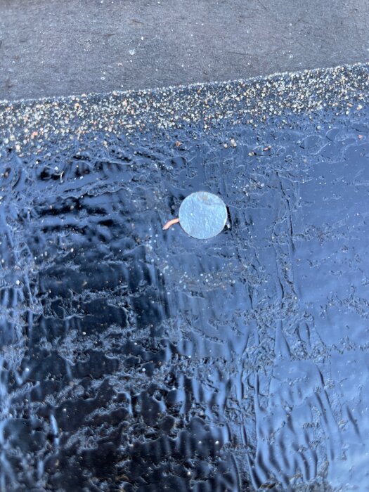 Spik genom svart tjock duk med grov yta nära kant av sandigt material, del av takrenovering.