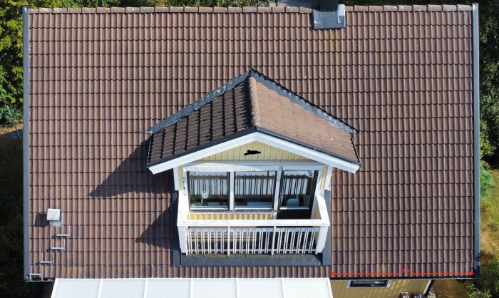 Takvy av hus med bruna pannor och ett uterum med vit ram och glasfönster under. Takfotens isolering och renovering diskuteras i inlägget.