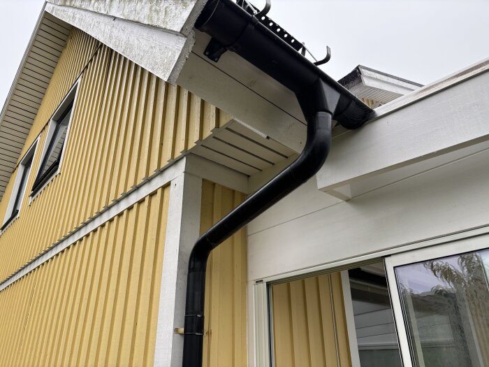 Takfot ansluter mot uterum på gult hus med svart hängränna; konstruktionen saknar isolering under takfoten.