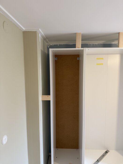 Ikea Pax garderob inbyggd i sovrum, med träregelklossar mot murstock.