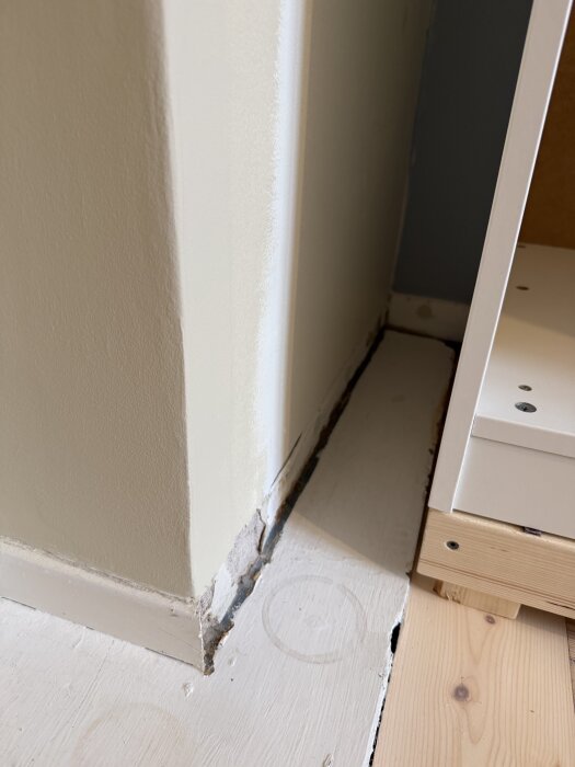 Vägghörn med murstock, golv och början av Ikea Pax garderob i ett rum under renovering.