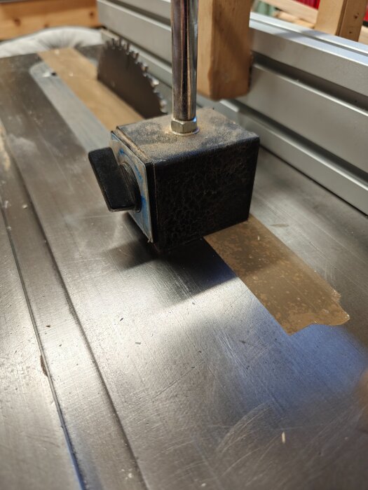 Bilden visar ett sågblad på en bordsåg med en mätklocka inställd för säkerhet när bokhylledörrar klyvs.