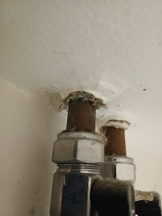 Rör med misstänkt asbestisolering i badrumstak, cirka byggår 1950. Närbild visar två rör med vit isolering runt öppningarna.