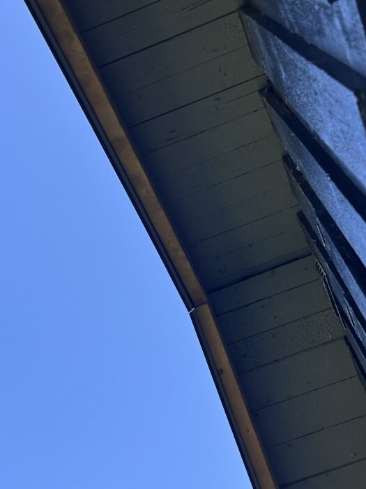 Hustak fotografi med blå himmel i bakgrunden, sett uppifrån nära takfoten.