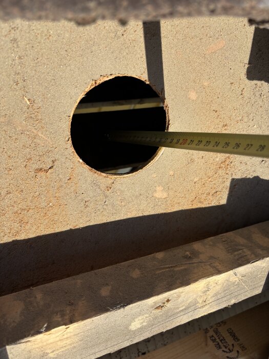 Inspektionshål i taket med måttband som mäter avståndet mellan innertak och masonite, cirka 120mm utrymme visas.