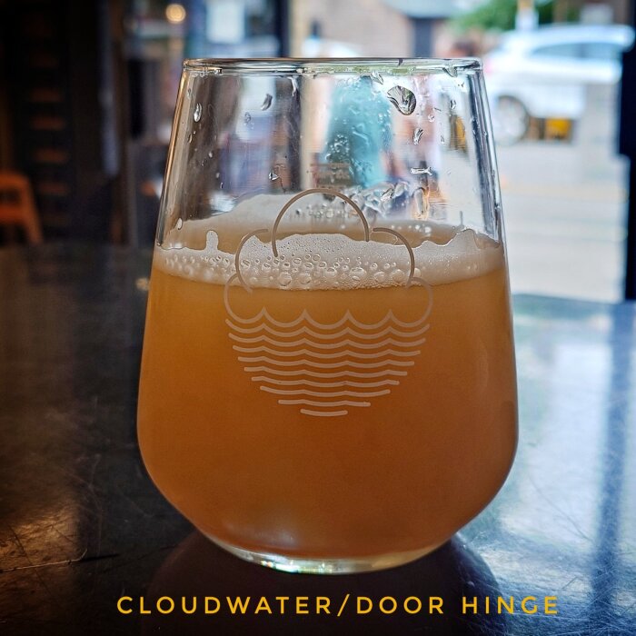 Ett glas med grumlig öl från Cloudwater-bryggeriet, placerat på ett bord.