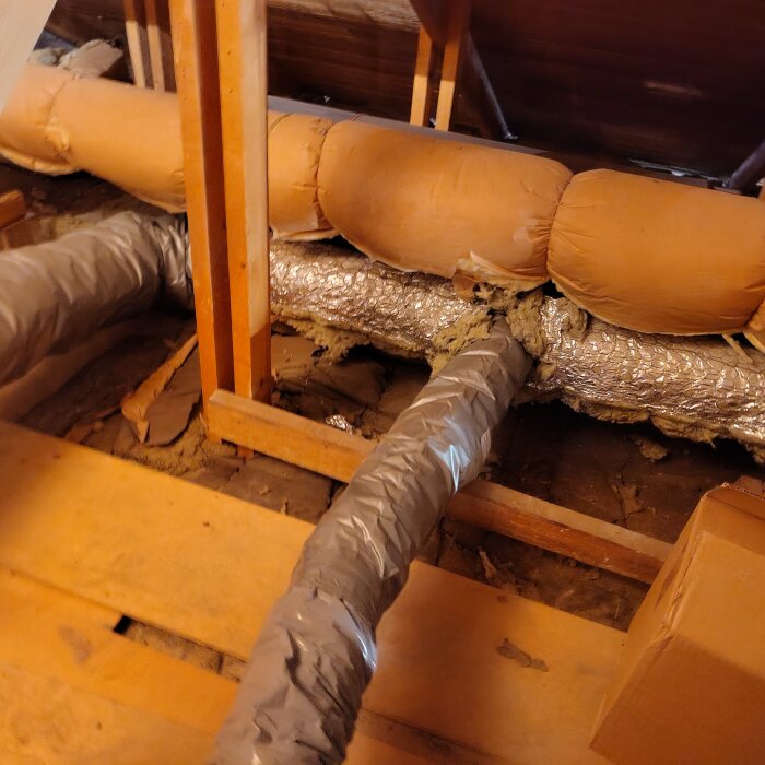 Ventilationssystem i vindsutrymme med silverfärgade och orange isolerade rör, visar till- och frånluftshantering före och efter installation av FTX-system.