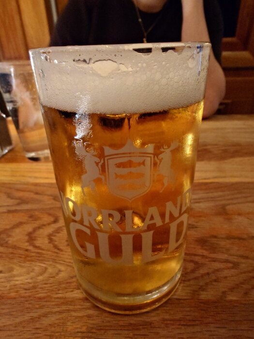 Ett glas Norrlands Guld öl på ett träbord på en pizzeria.