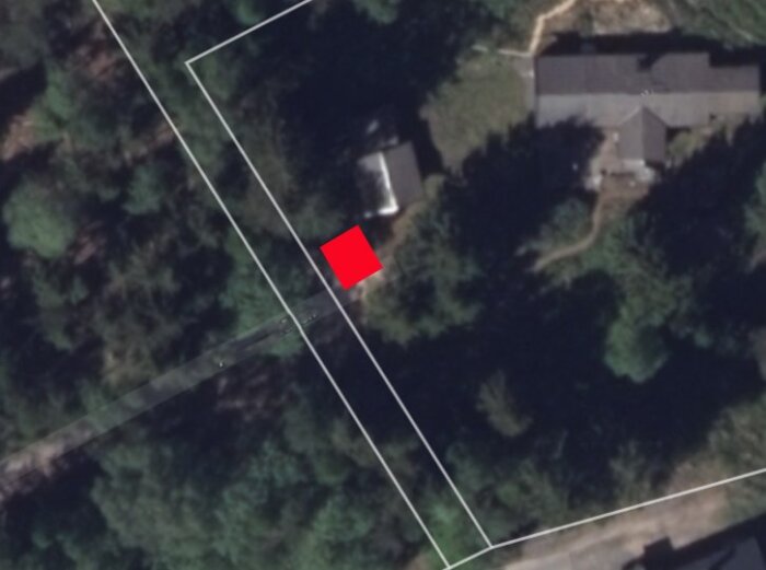 Satellitbild av en tomt vid skogskanten med en röd markering på tomtgränsen där en carport planeras att byggas.