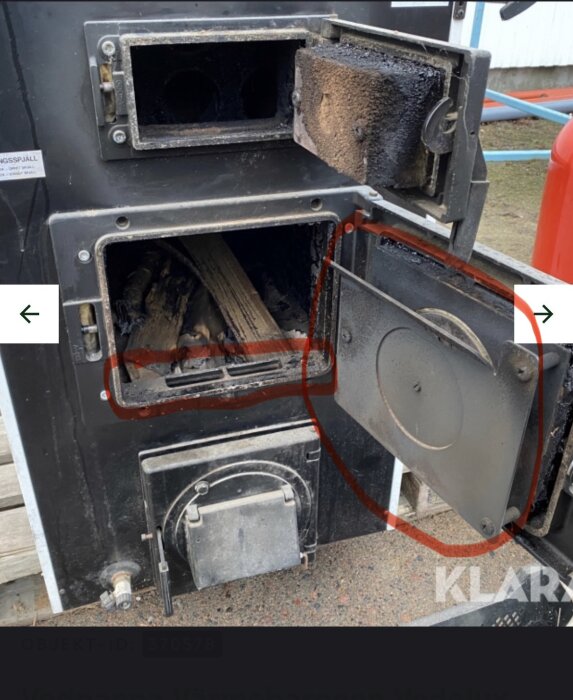 Bild av en vedpanna med öppna luckor, visar insidan av brännkammaren och nyinstallerad plåt för bättre primärluftcirkulation.