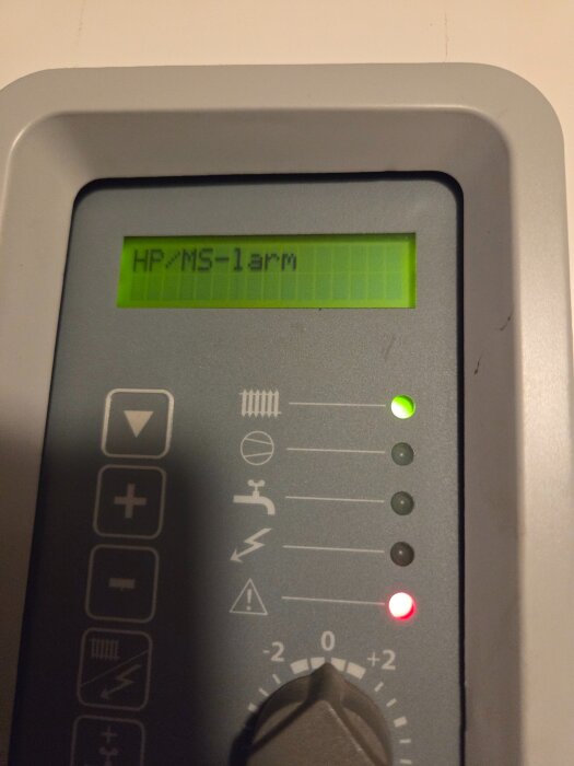 Grå kontrollpanel med grön LCD-skärm som visar texten "HP/MS-1 larm". LED-lampor lyser grönt och rött, symboler och justerknapp syns.