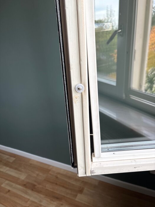 Öppet fönster med delvis synlig träram som släppt och plastdelar som separerar inner- och ytterfönster.