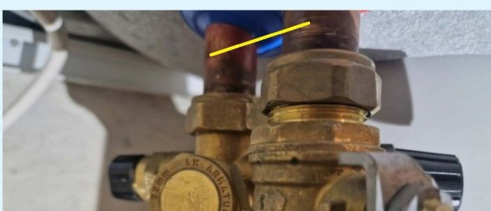 Bild av vattenrörsanslutningar med klämringskoppling och en gul linje som markerar avståndet; rören mäter 22 mm i diameter.