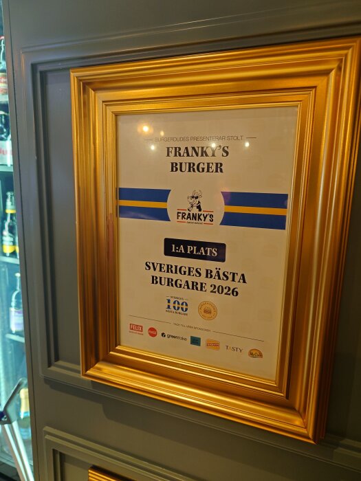 Guldinramad utmärkelse för "Franky's Burger", utsedd till Sveriges bästa burgare 2026, med sponsornamn längst ner.