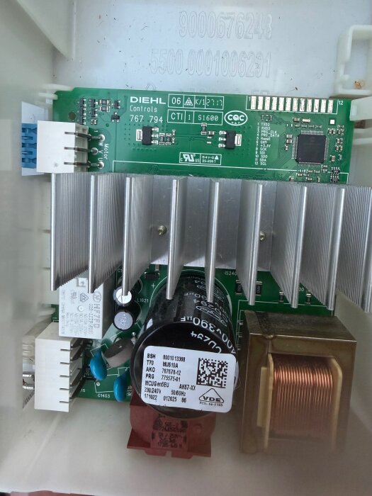 Elektroniskt kretskort med olika komponenter, inkl. kondensator, kopparspole och kylflänsar, märkt "Diehl Controls".