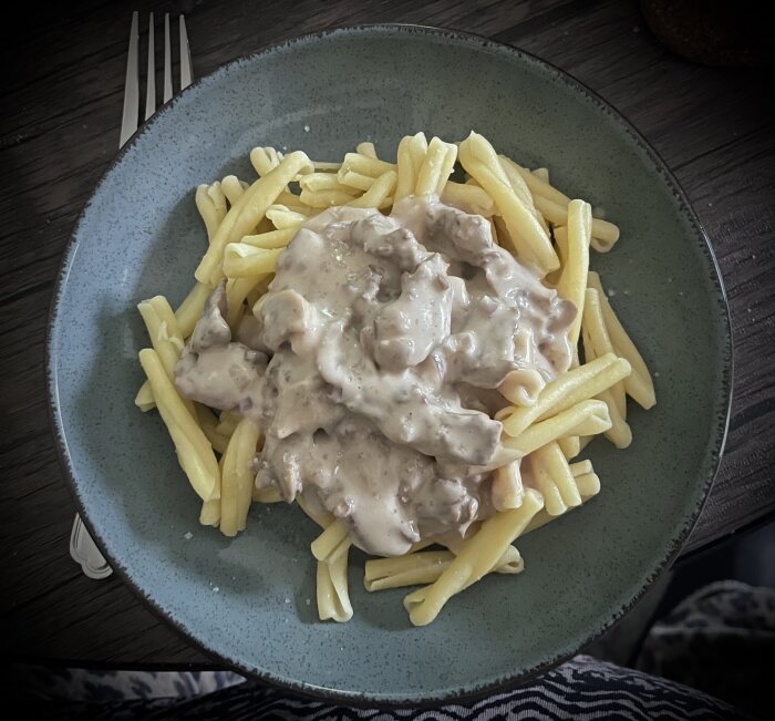Pasta med entrecote-strimlor, champinjoner och gorgonzolasås på en tallrik.