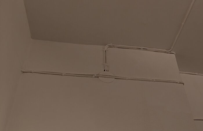Kabeldragning längs väggen, med flera kablar som går i olika riktningar och möts vid en central punkt.