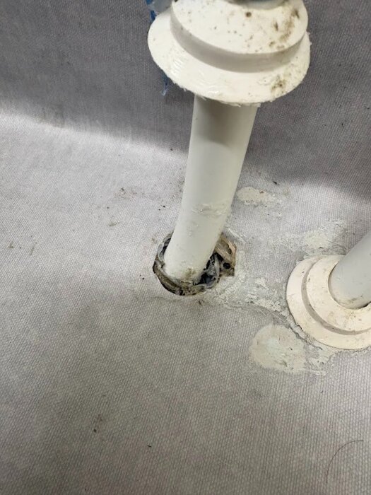 Rörgenomföring i grått golv med ojämn fogning, eventuellt tecken på byggfel.