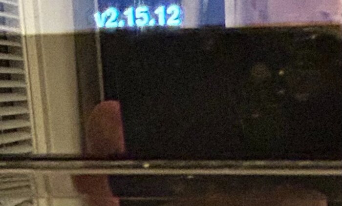 Närbild på ett delvis fyllt plastkärl, reflektioner i glaset och texten "v2.15.12" syns svagt i bakgrunden.