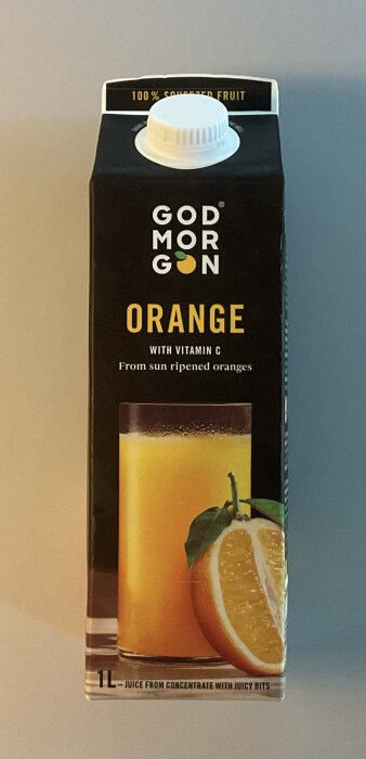 Förpackning av God Morgon apelsinjuice med vitamin C och bild på ett glas juice och en halv apelsin.