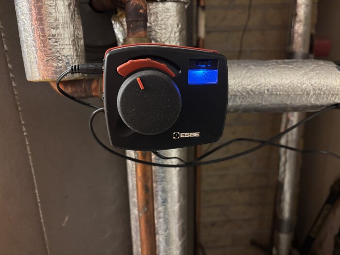 En ESBE CRA211 shuntautomatik installerad på en isolerad vattenledning med synlig temperaturomätning på displayen.