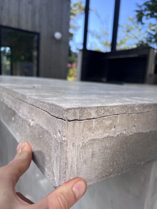 Spricka i gjuten betongskiva för utekök, visar spricka som går ca 5 cm in från kanten, med fokus på materialets lager och sprickans påverkan.