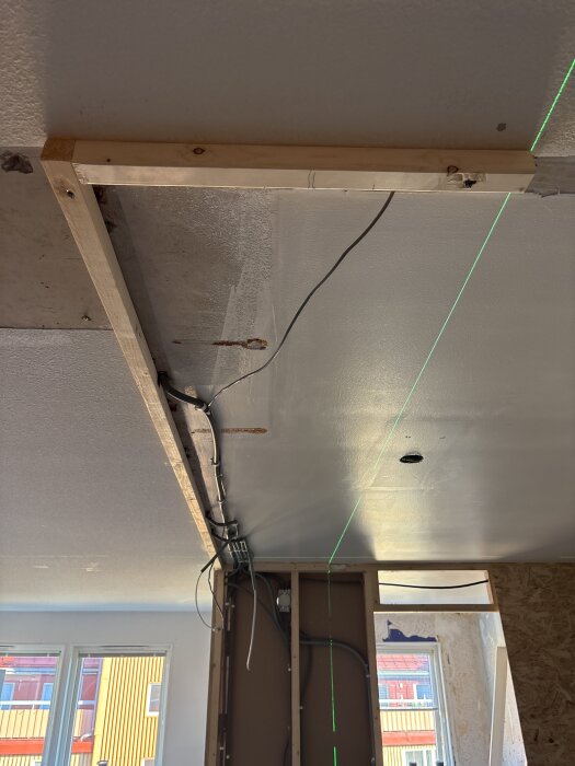 Träram i taket med synliga sladdar och laserlinje för byggprojekt att installera spotlights och gömma kablar.