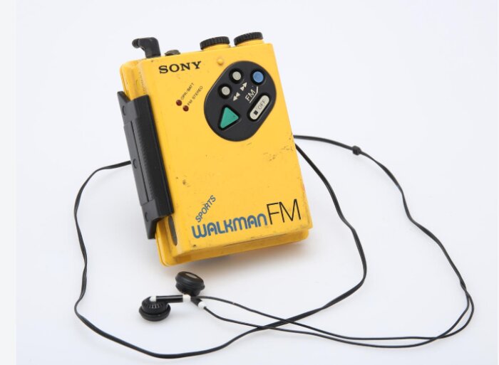 Gul Sony Walkman Sports FM med svarta hörlurar, bärbar kassettspelare från 80-talet.