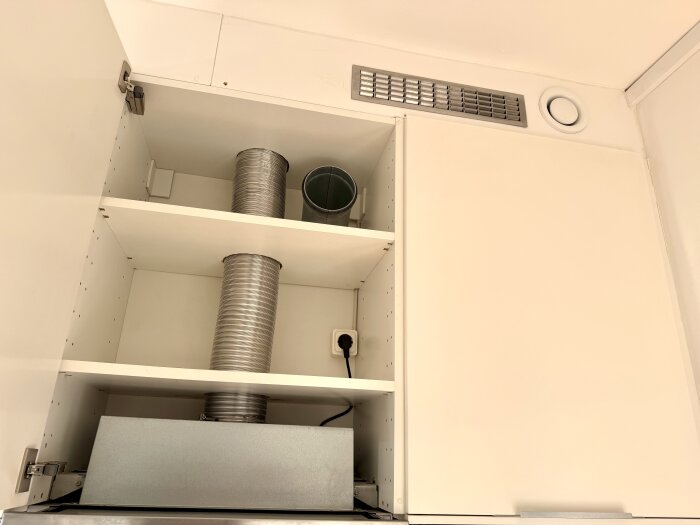 Köksöverskåp med ventilationsrör och ventilgaller ovanför utdragbar köksfläkt.