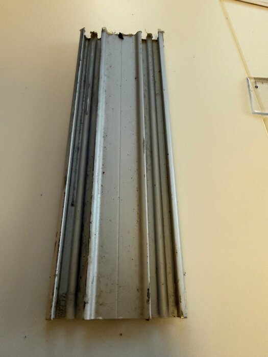 Metallskena för skjutdörrar med två spår, tagen mot en ljus bakgrund.
