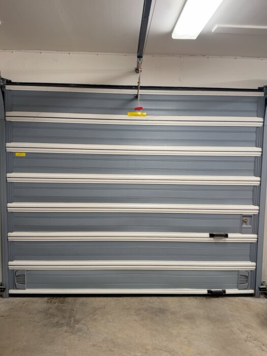 Grå och vit sektionerad Crawford garageport med synliga handtag och bottenlist i en upplyst garageinteriör.