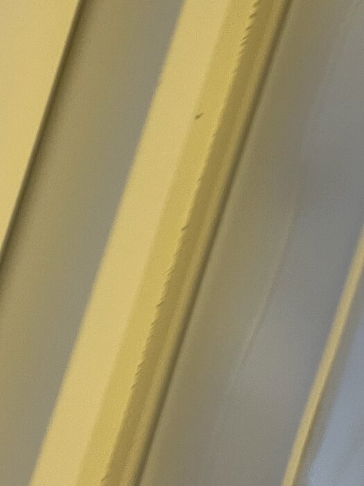 Nära närbild på en del av ett tak med gul tejp som verkar dra med sig färg från träet efter installation av ett Veluxfönster.