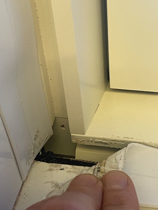 Närbild av fönsterkarm med skadad färg och trasigt tätningstejp; behov av list för att täcka öppna kanter syns.