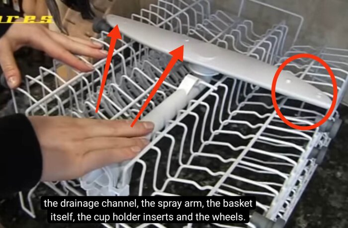 En person visar en diskmaskin där den övre korgen har några nedåtriktade hål på sprutarmen i en billig Electrolux diskmaskin.