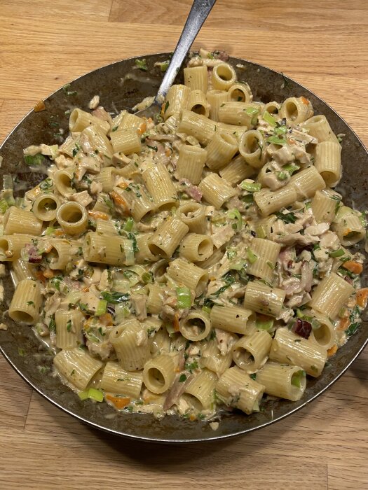 Pasta Alfredo med kyckling, purjolök, och kryddor i en gräddig sås på en tallrik.