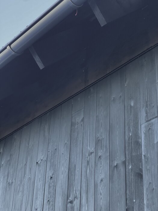 Träpanel och takränna på ett hus, synliga detaljer av fasaden.