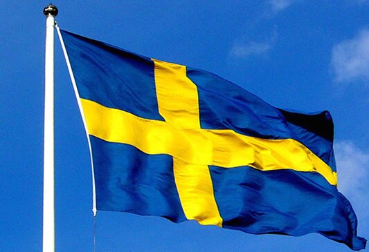 Svenska flaggan vajar mot blå himmel.
