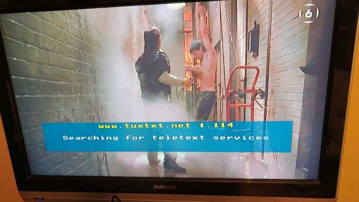 TV-skärm med pågående film och textremsan "Searching for teletext services" från teletexthanterare tuxtext.net.